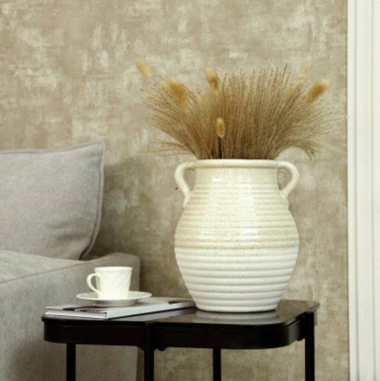 Calen Urn Vase, white two-handled ribbed urn with dried pampas on a black side table by a teacup