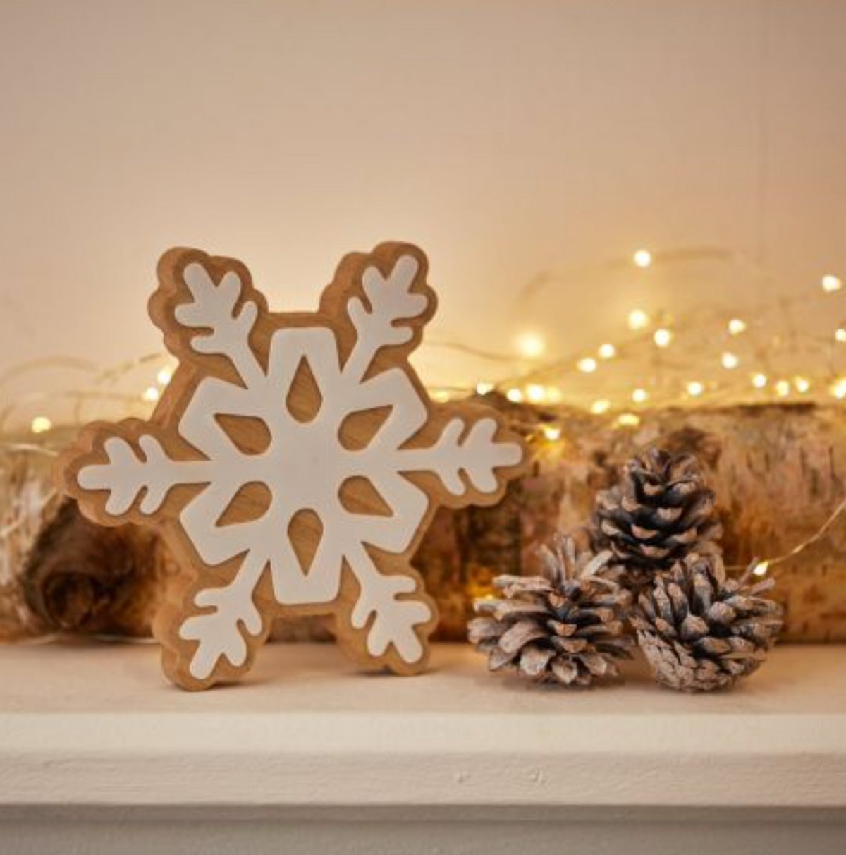 Medium Wooden Standing Snowflake Decoration on a shelf with pine cones and fairy lights
