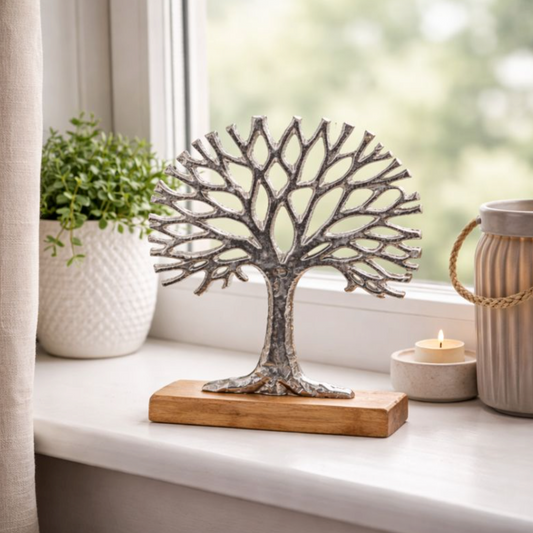 Silver Tree of Life Ornament on Wooden Base on a sunny windowsill beside plants