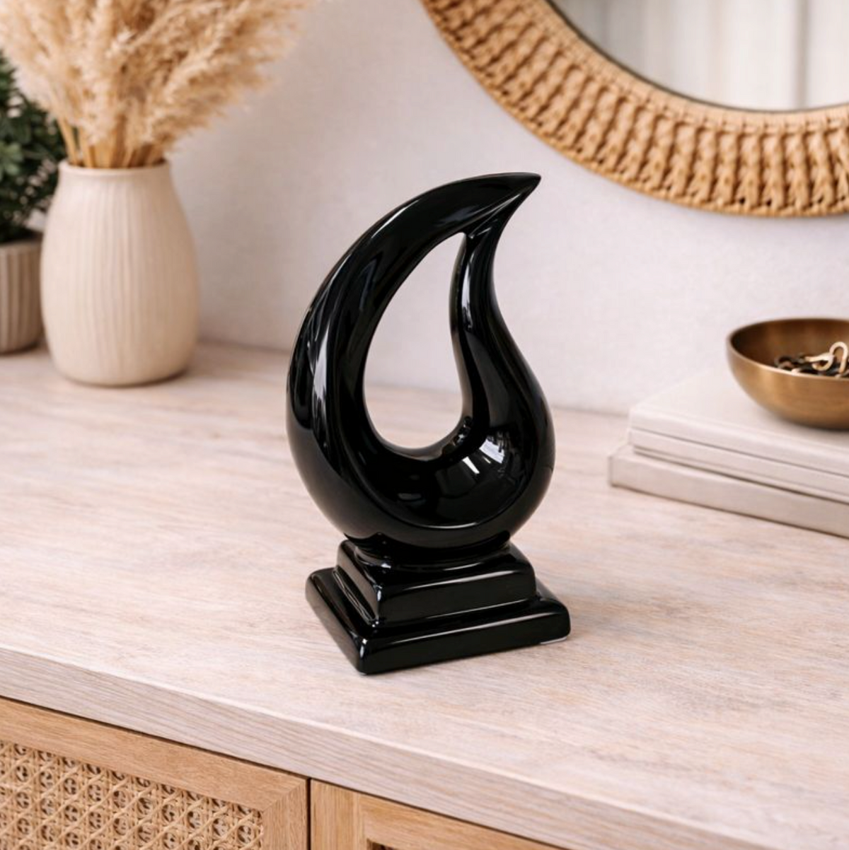 Tario Styling Piece Black shown on a light console with a rattan mirror, dried grass and a gold bowl