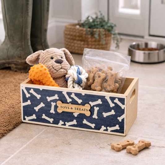 Wooden Dog Toy & Treat Storage Crate with navy bone pattern, on the floor with toys and dog biscuits by a bowl