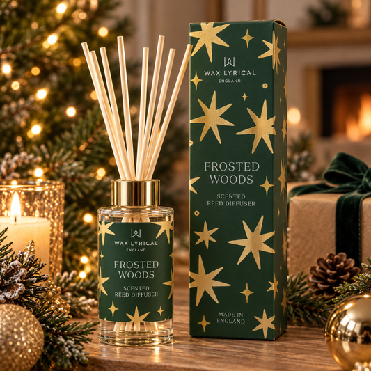 Frosted Woods Reed Diffuser, 100ml, with its dark green gold-starred box by a lit Christmas tree