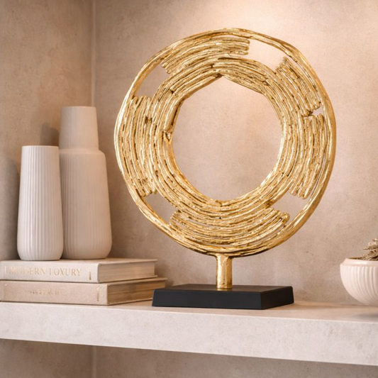 Aurelia Halo Gold Metal Sculpture, Large, textured gold ring on a black stand on a shelf