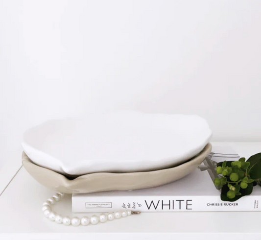 Bailey Styling Plate, a white oval plate with a scalloped edge, resting on books with a string of pearls