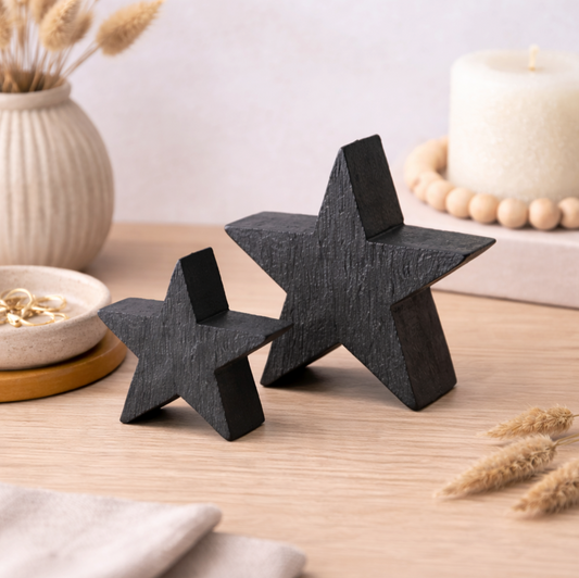 Black Mango Wood Star Ornament, Medium beside a smaller star on a table with candles
