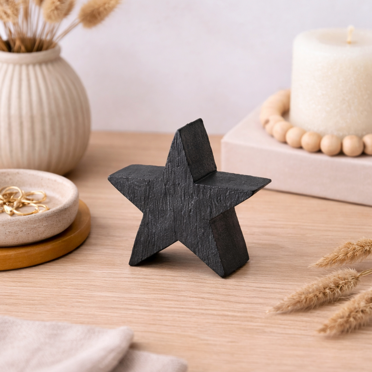 Black Mango Wood Star Ornament, Small, chunky black wooden star on a table by a candle