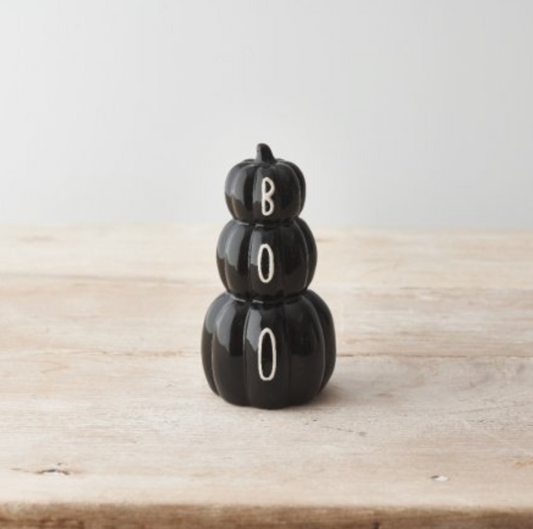 Black Pumpkin Stack of three black pumpkins with white BOO lettering, on a plain pale surface
