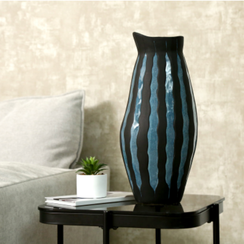 Blue Ember Ceramic Vase in black and blue ribbed glaze on a black side table beside a small plant