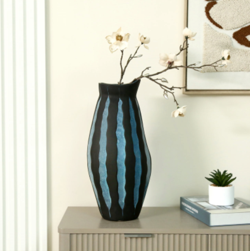 Blue Ember Ceramic Vase, a curvy black vase with blue drip glaze stripes holding white blossom
