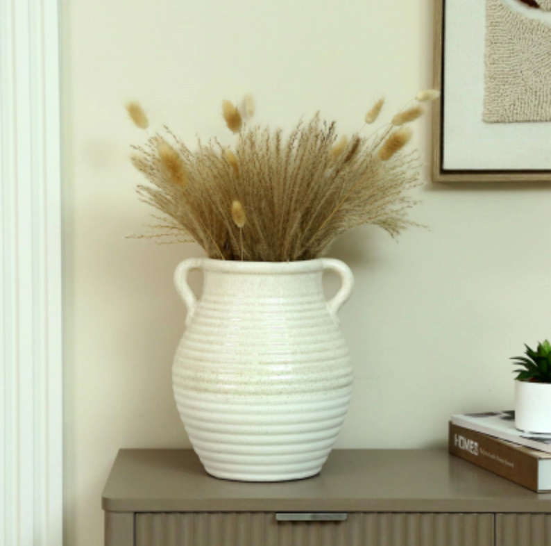 Calen Urn Vase, white ribbed urn with fluffy dried grasses on a grey sideboard beside a small plant