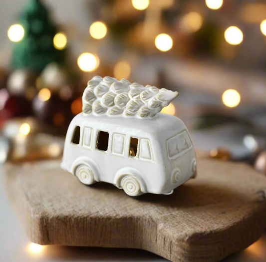 Ceramic LED Camper with Tree, a white camper van with a tree on its roof, windows lit, against fairy lights