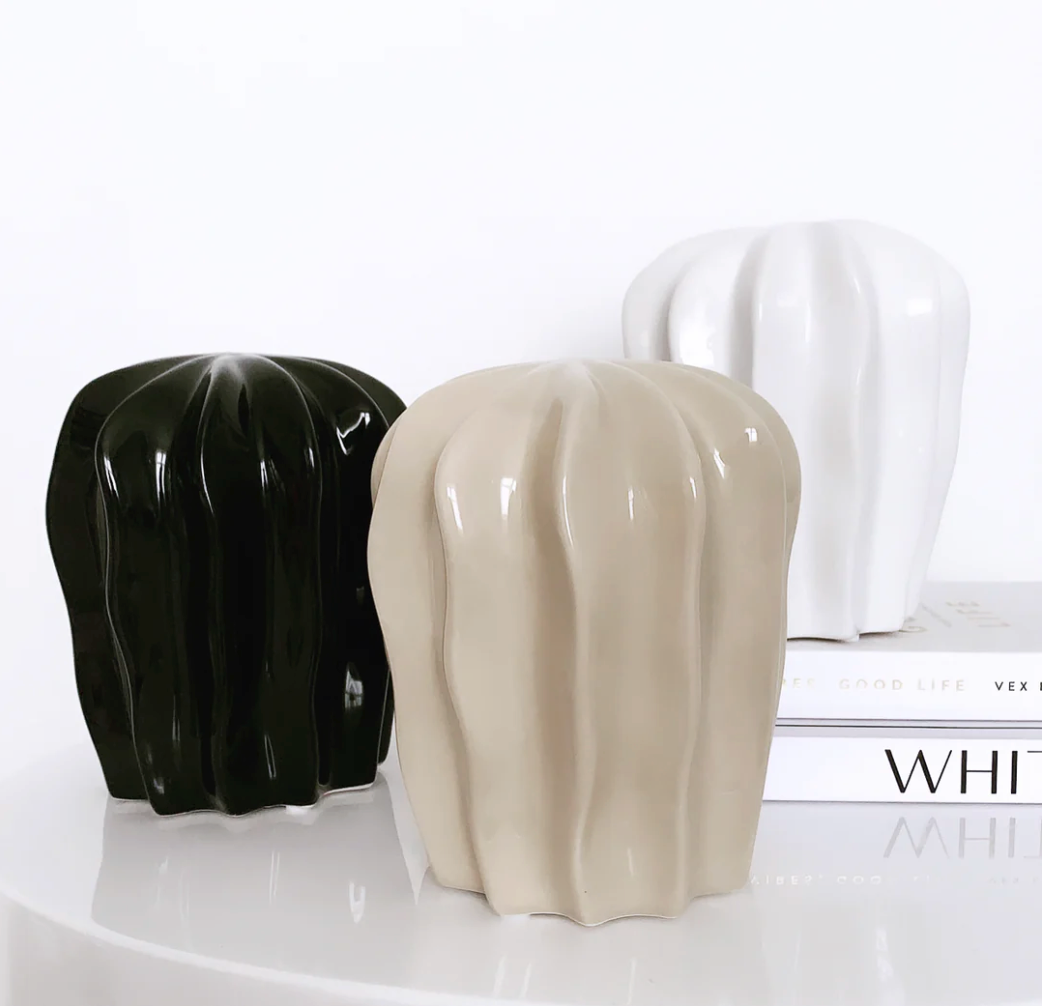 Fiji Styling Piece Nude shown with black and white versions of the ribbed ornament, standing on books