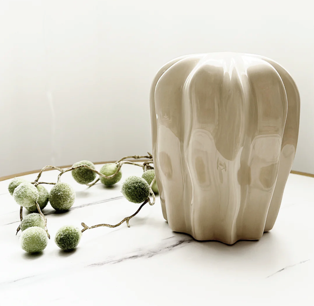 Fiji Styling Piece Nude, a cream ribbed ceramic ornament with a wavy profile, on marble with greenery