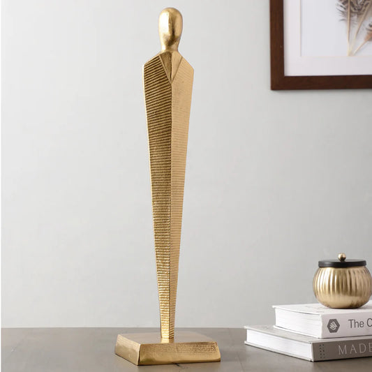 Gold Metal Sculpture 64cm, tall slim abstract figure on a sideboard beside books and a framed print