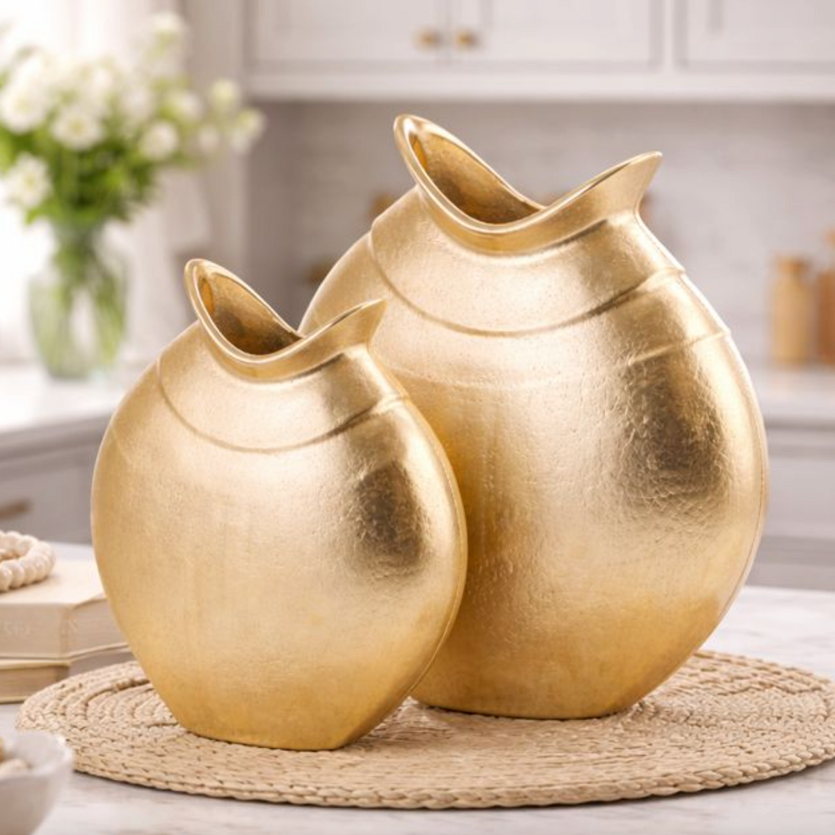 Helios Gold Metal Vase, Medium, shown with a larger matching gold vase on a woven placemat