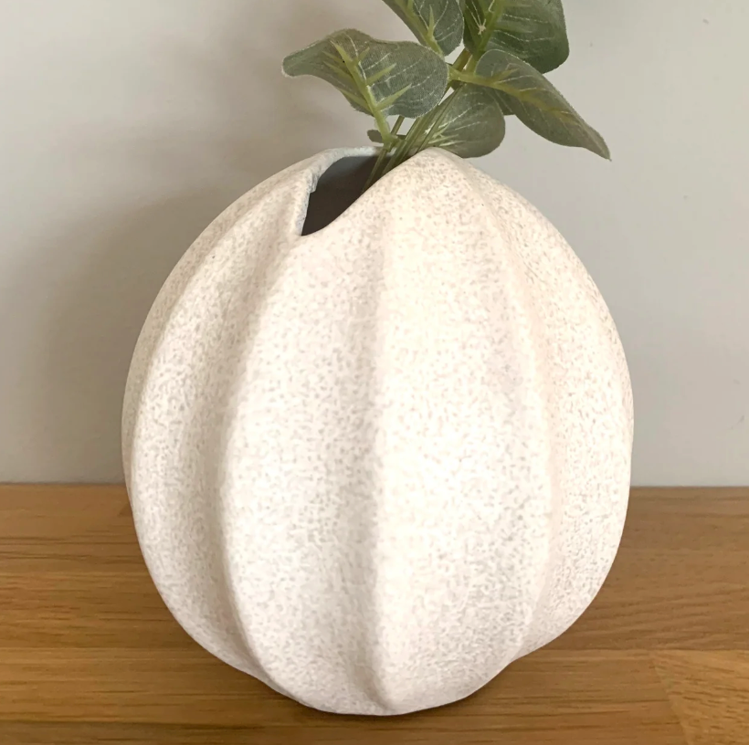 Nova Vase - Textured Effect in speckled white, holding a sprig of greenery on a wooden table