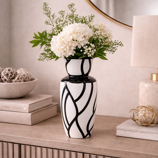 Obsidian Flow Vase, white with black swirling lines, holding white flowers on a sideboard