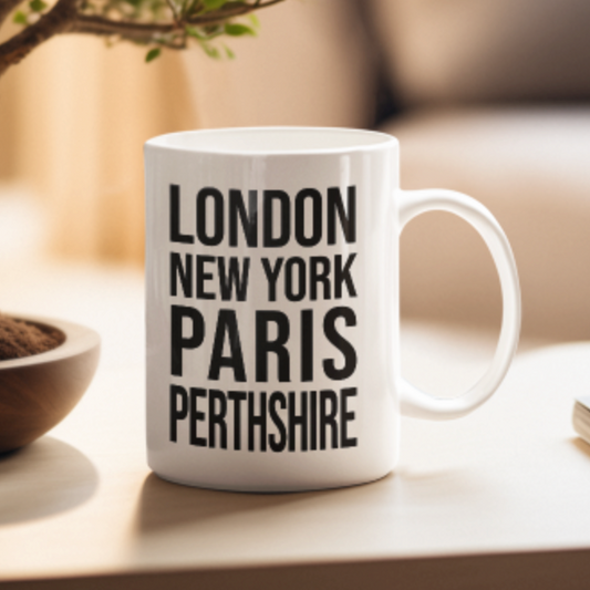 PERTHSHIRE Mug in white with bold black lettering, on a light table in soft morning light