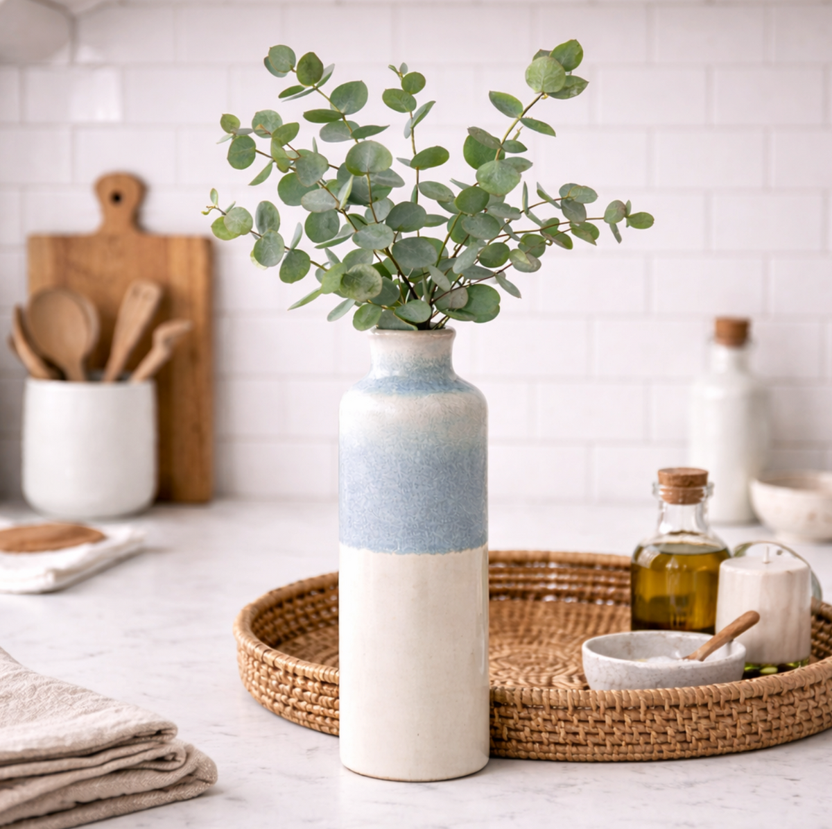 Serene Blue Reactive Glaze Vase, Large beside a rattan tray and chopping boards