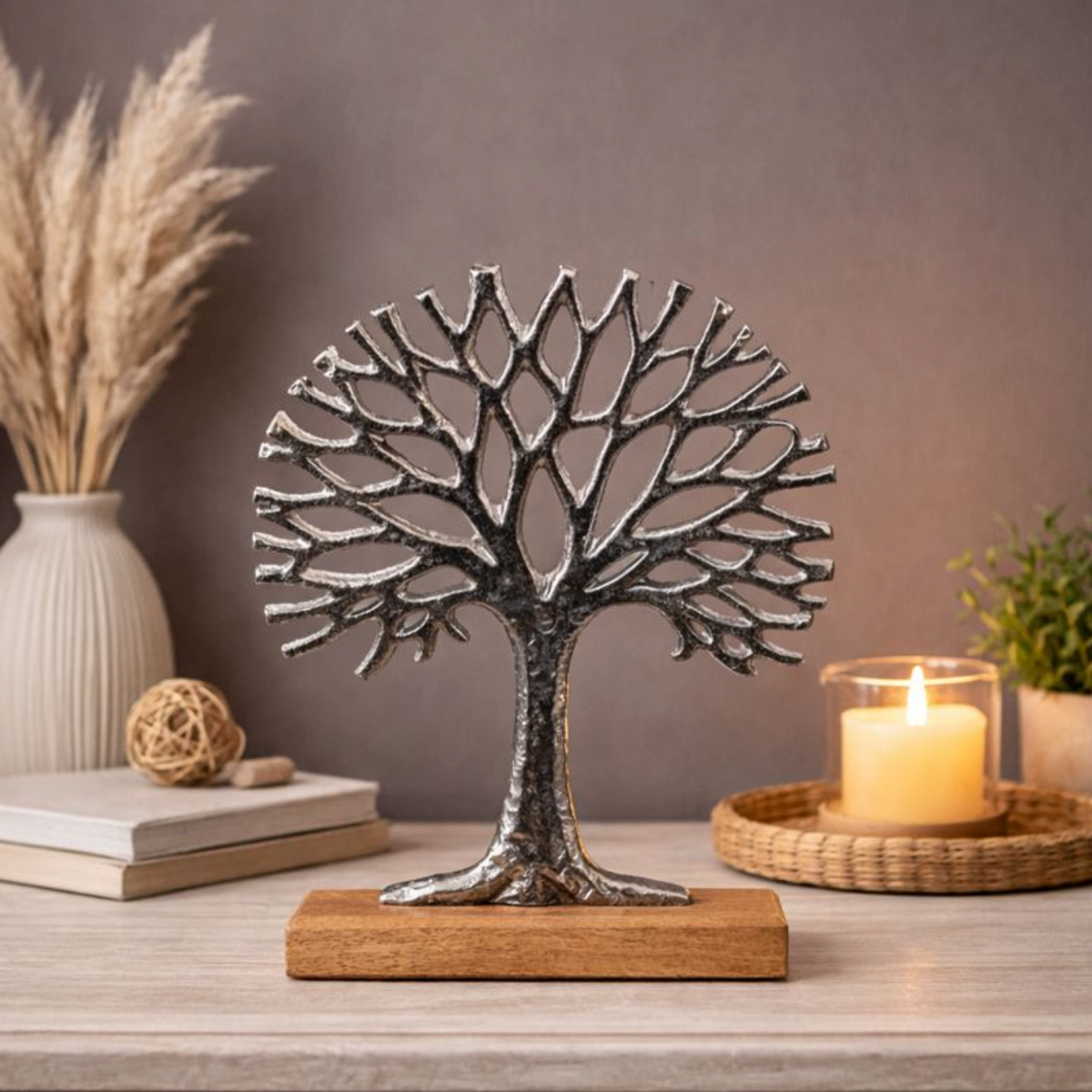 Silver Tree of Life Ornament on Wooden Base beside candles and dried grasses