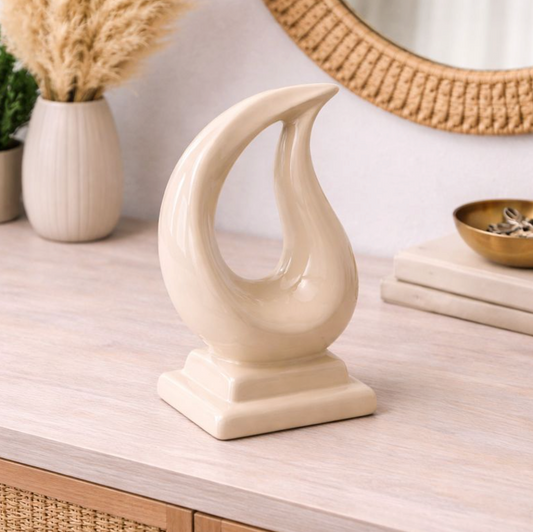 Tario Styling Piece Nude, a cream flame-shaped ceramic ornament on a stepped base, on a console table
