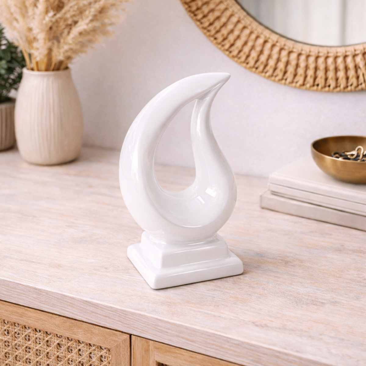Tario Styling Piece White, a glossy white curved flame-shaped ornament on a console with a rattan mirror