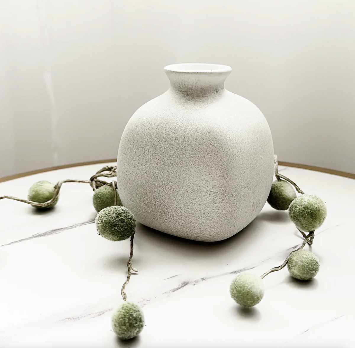 Tasha Vase (Various Colours), a white speckled bottle-shaped vase on a marble surface with greenery