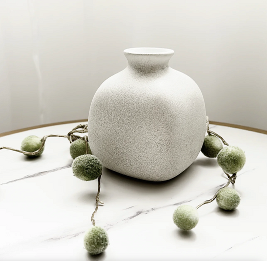 Tasha Vase (Various Colours), a white speckled bottle-shaped vase on a marble surface with greenery