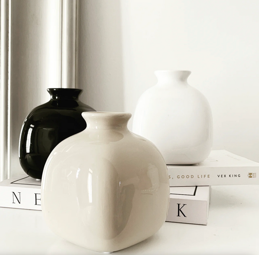 Tasha Vase (Various Colours) in white and black gloss, grouped together on a shelf with books